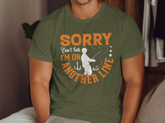 Green t-shirt with text "Sorry, I can't talk, I'm on another line" and fishing graphic.