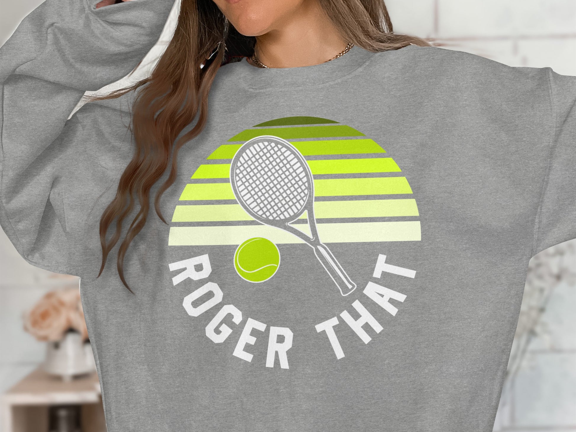 Grey sweatshirt with "Roger That" text and tennis racket and ball graphic.