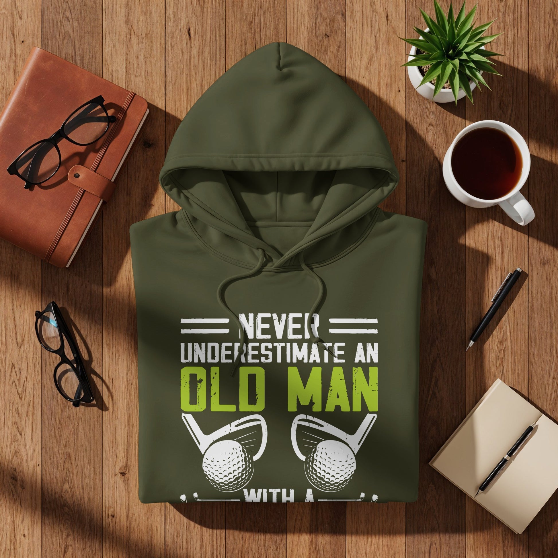 Olive green hoodie with text "Never underestimate an old man" and golf balls.
