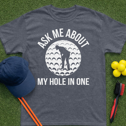Dark gray t-shirt with "Ask Me About My Hole In One" and golf ball graphic.