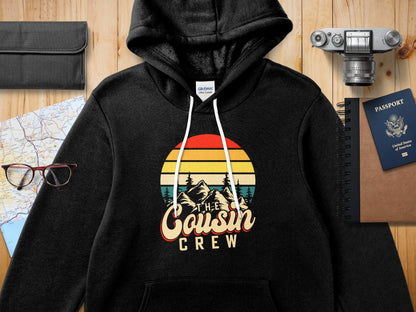 Black hooded sweatshirt with "The Cousin Crew" retro sunset graphic.