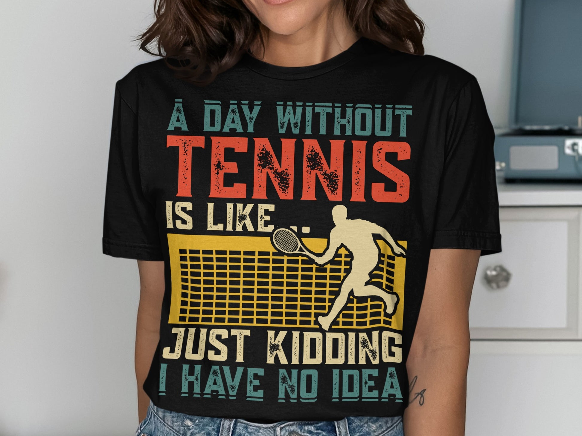 Black t-shirt with orange and teal text "A day without TENNIS is like JUST KIDDING I HAVE NO IDEA".