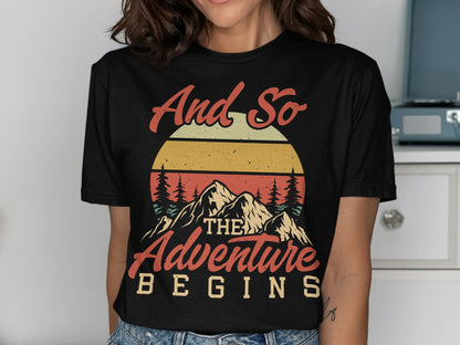 Black t-shirt with mountains, sunset, and text "And so the adventure begins".
