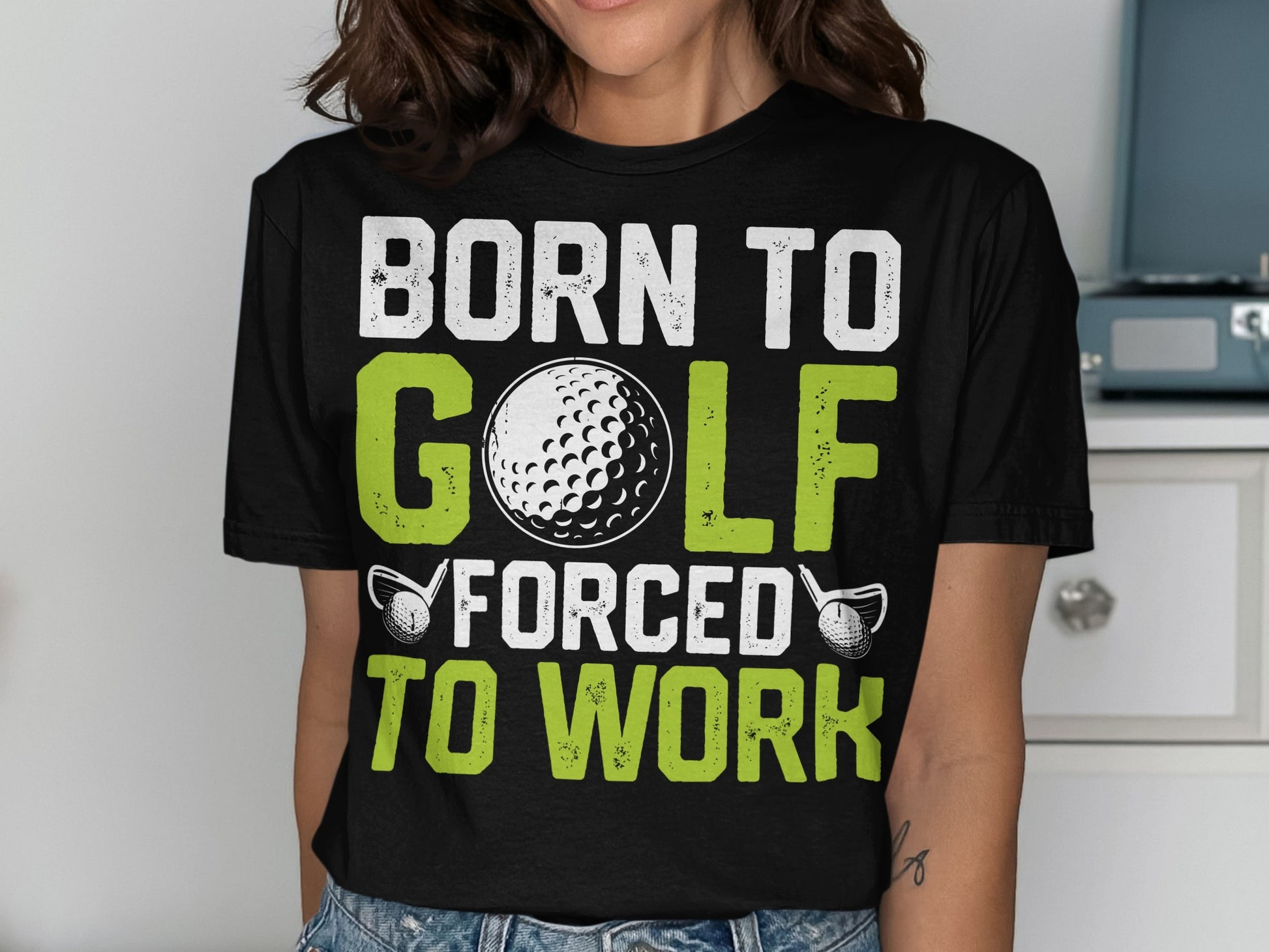 T-shirt with "BORN TO GOLF FORCED TO WORK" text and golf ball graphic.