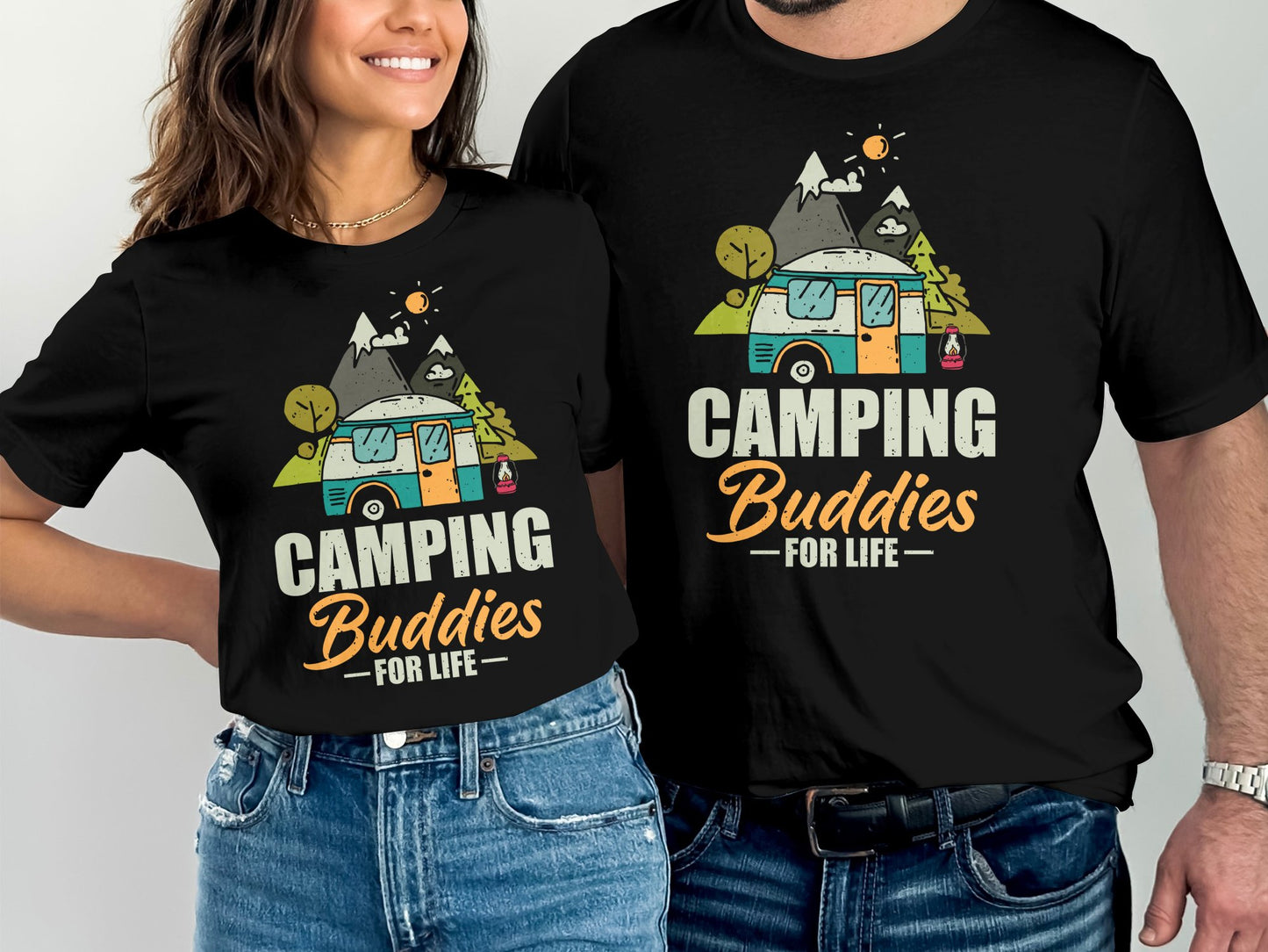 Two people wearing matching black t-shirts with a camper and mountains design.