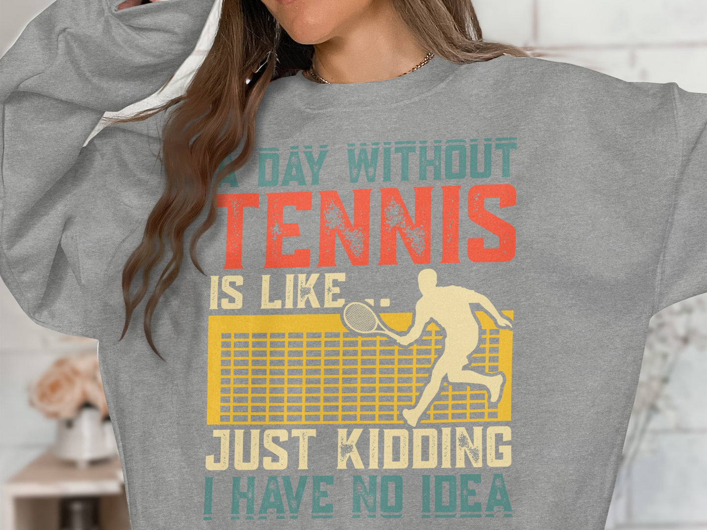 Gray sweatshirt with "A Day Without Tennis Is Like Just Kidding I Have No Idea" text and tennis graphic.