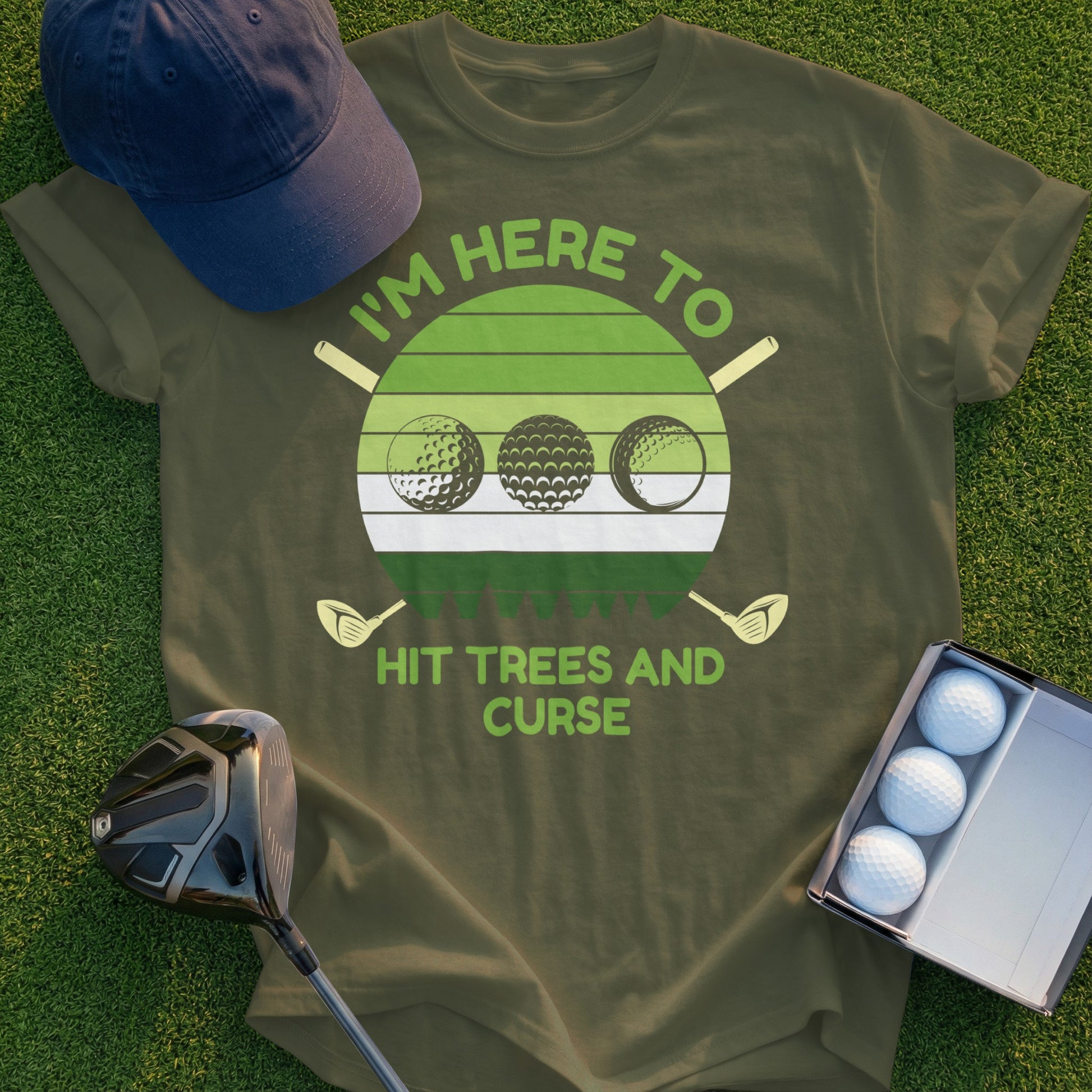 Olive green t-shirt with "I'm here to hit trees and curse" text and golf balls.