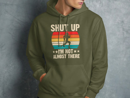 Green hoodie with runner graphic and text "SHUT UP I'M NOT THERE".