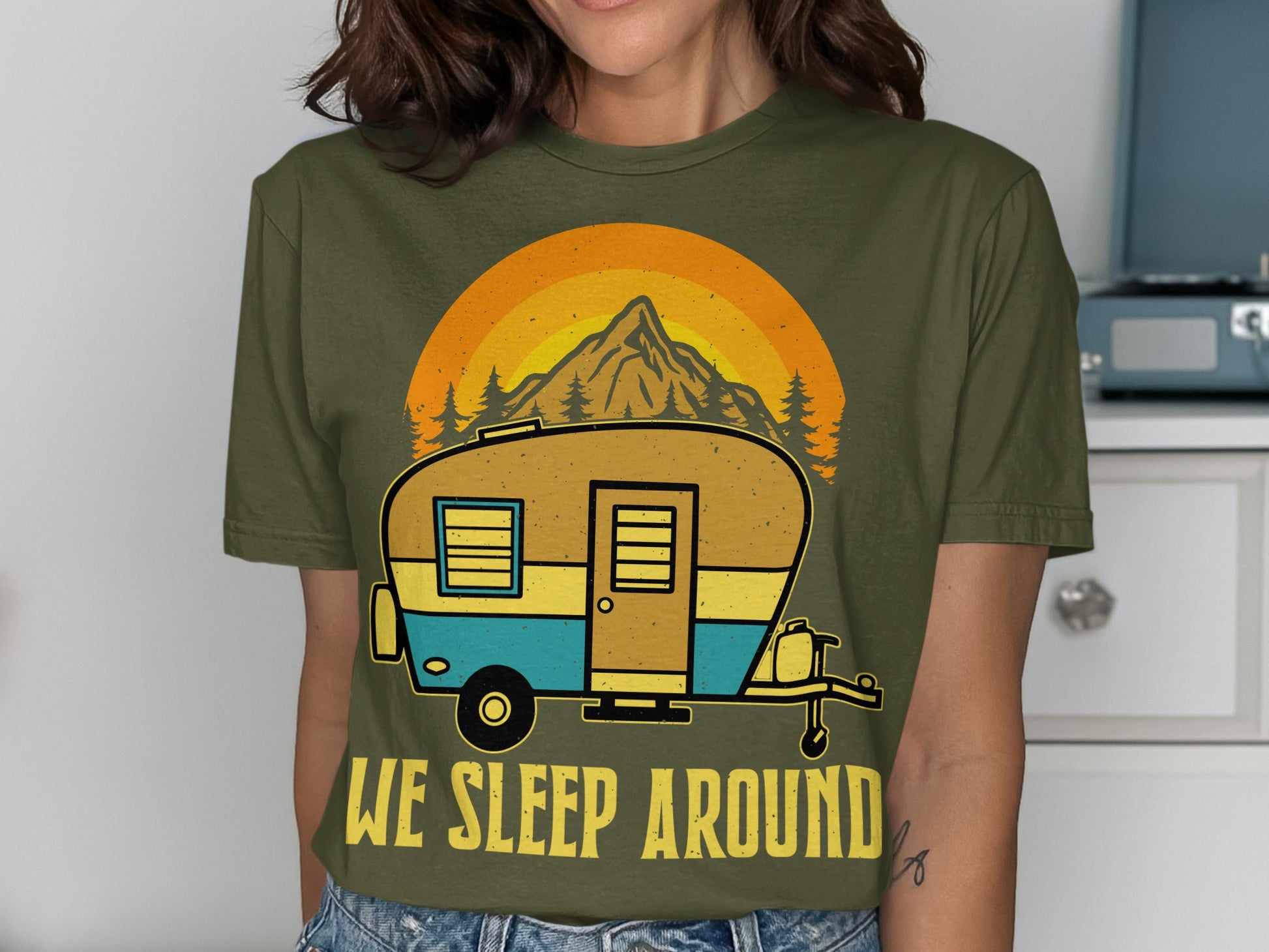 Green t-shirt with a retro camper graphic and "We Sleep Around" text.