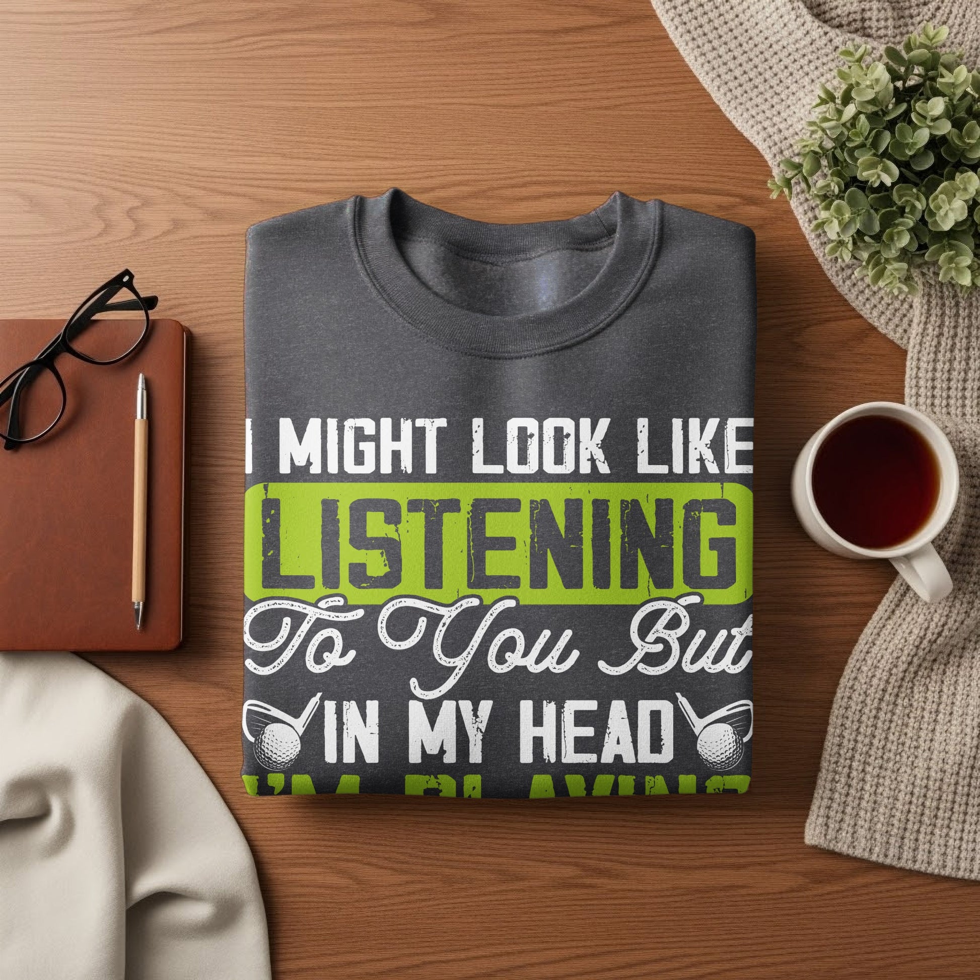 Dark grey t-shirt with white and green text "I might look like I'm listening to you but in my head".