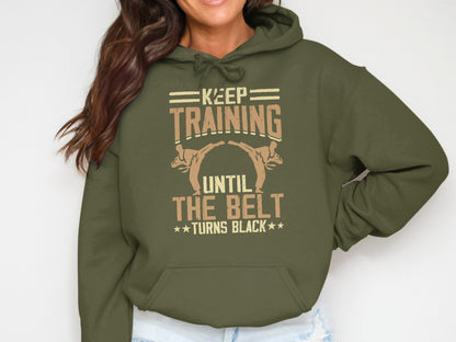 Green hoodie with "Keep Training Until The Belt Turns Black" in white and orange text.