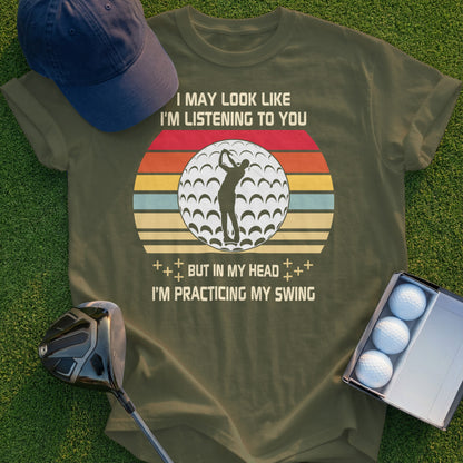 Olive green t-shirt with "Practicing my swing" golf graphic and text.