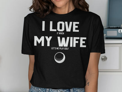 Black t-shirt with text "I love my wife lets me play golf" and a golf ball graphic.