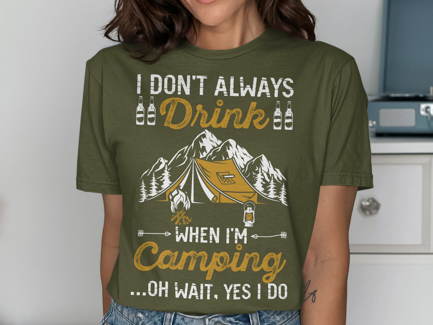 Olive green t-shirt with tent and mountain graphic and text.