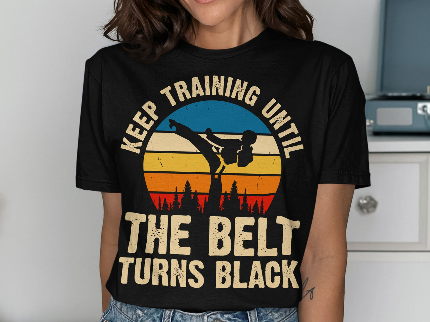 Black t-shirt with sunset graphic and text "Keep training until the belt turns black".