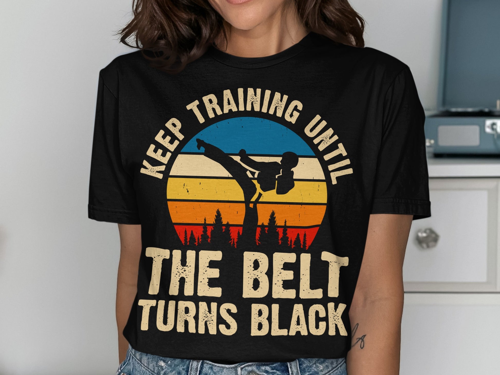 Black t-shirt with sunset graphic and text "Keep training until the belt turns black".
