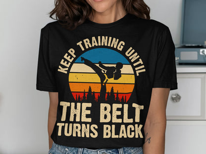Black t-shirt with sunset graphic and text "Keep training until the belt turns black".