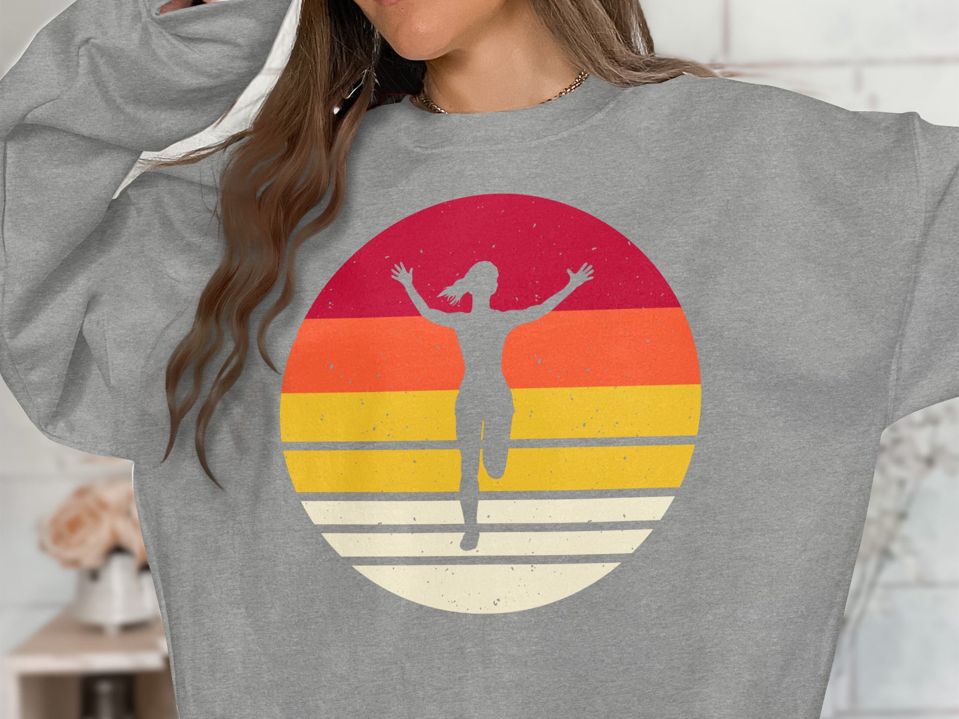 Grey sweatshirt with a circular graphic of a running figure against a sunset.