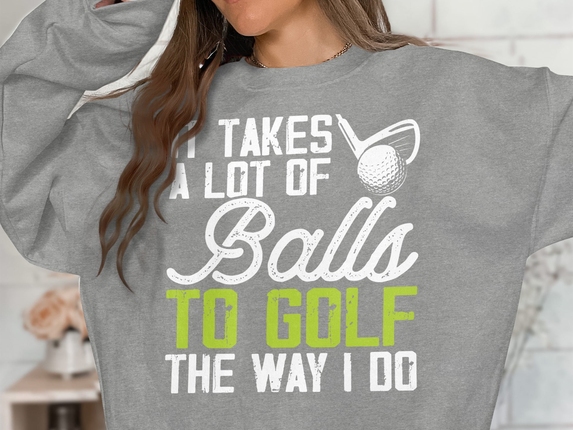 Grey sweatshirt with "It Takes A Lot Of Balls To Golf The Way I Do" text and golf ball.