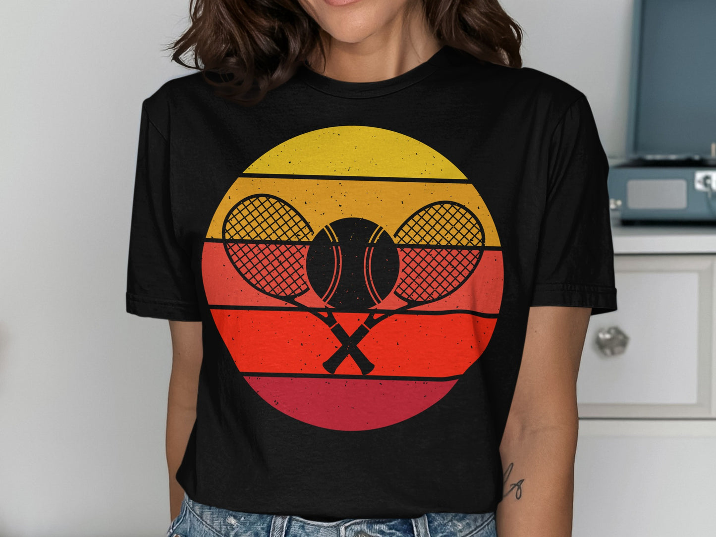 Black t-shirt with crossed tennis rackets and ball on a sunset graphic.