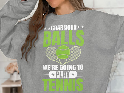 Grey sweatshirt with "Grab your balls we're going to play tennis" and tennis rackets.