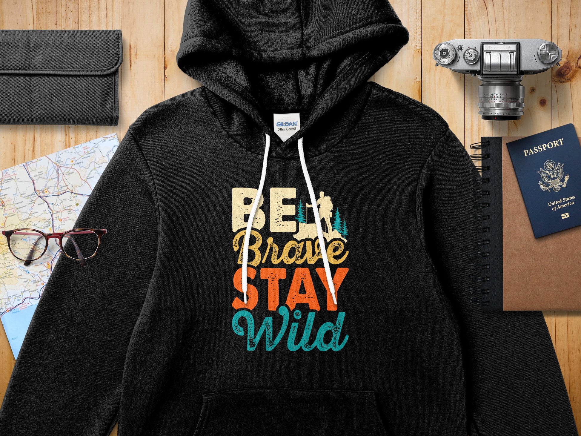 Black Gildan Ultra Cotton hoodie with "BE BRAVE STAY WILD" text.