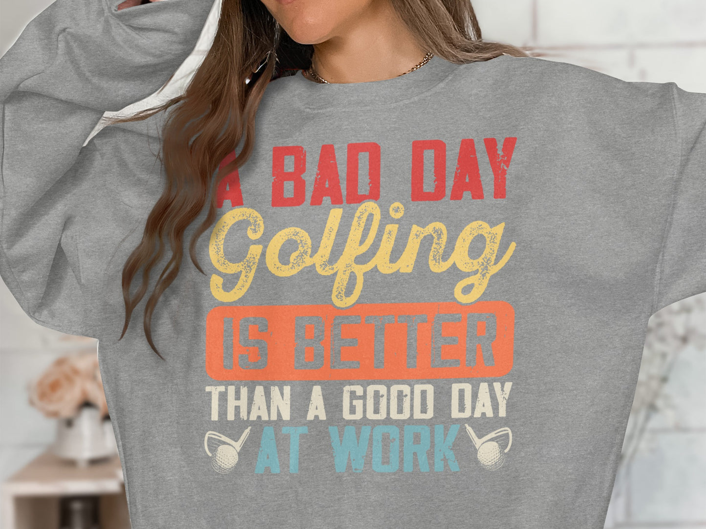 Grey sweatshirt with "A bad day golfing is better than a good day at work" text.