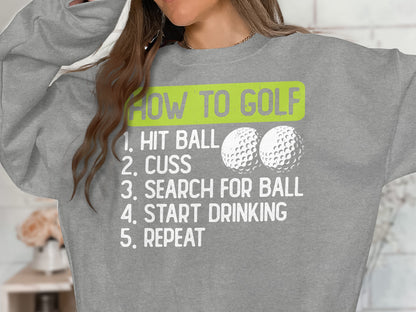 Gray sweatshirt with "How to Golf" humorous steps listed in white text.