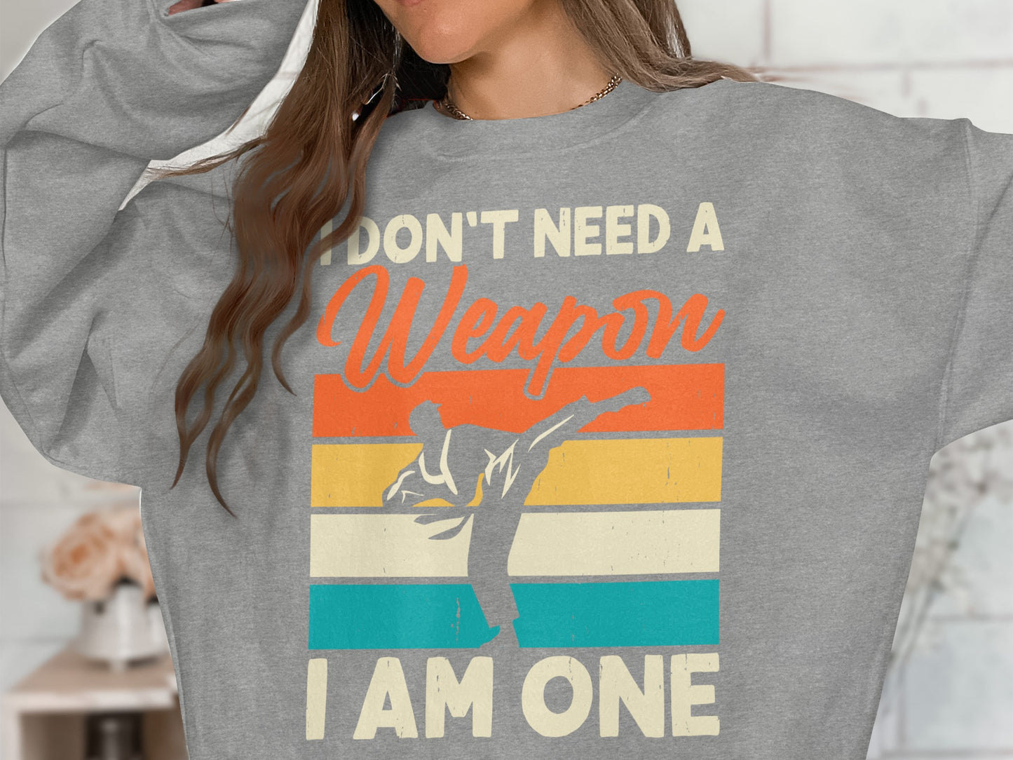 Grey sweatshirt with "I DON'T NEED A WEAPON I AM ONE" and karate silhouette.