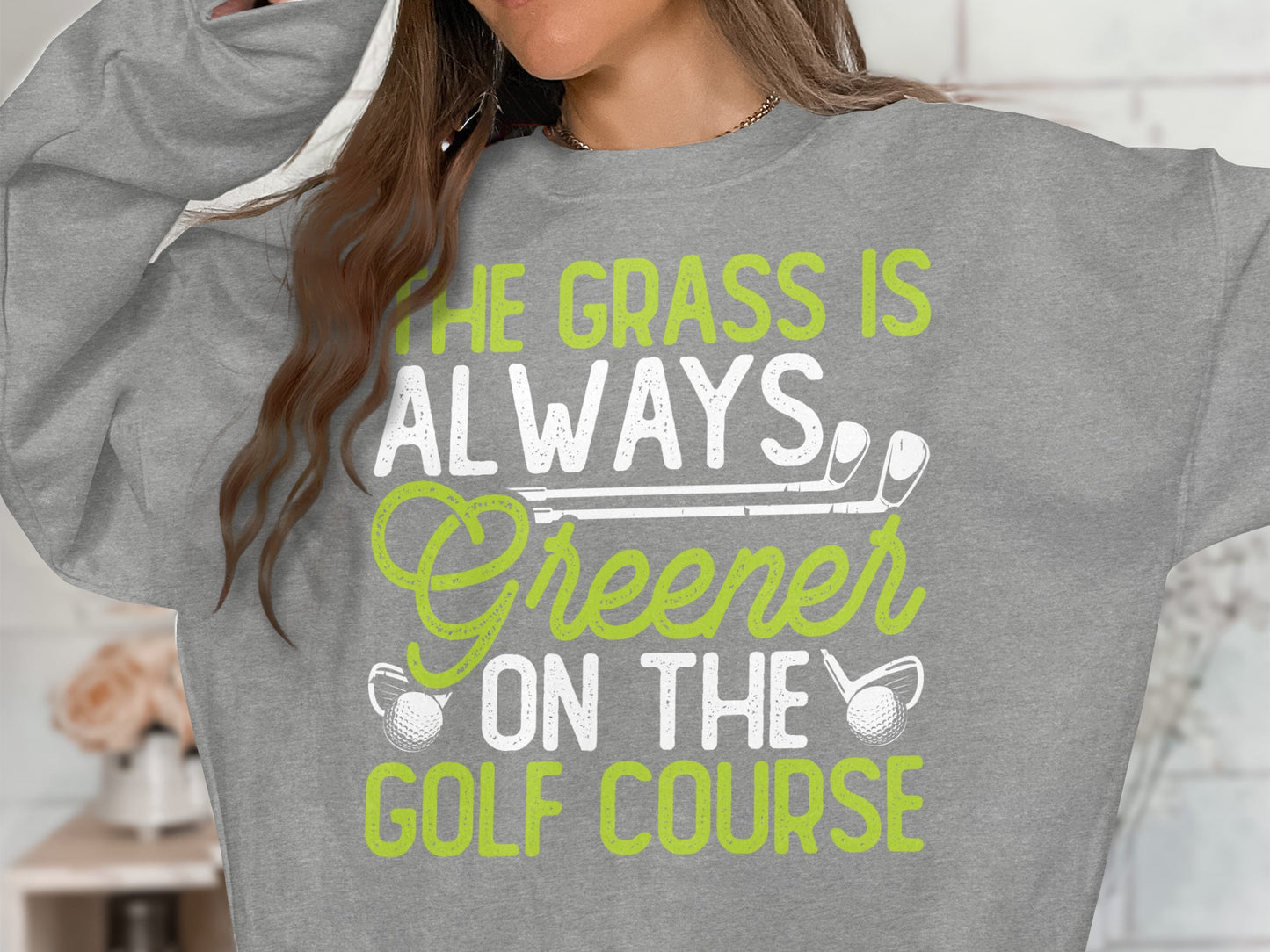 Sweatshirt with text "The grass is always greener on the golf course" and golf club graphics.