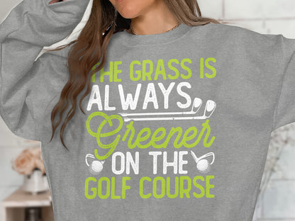 Sweatshirt with text "The grass is always greener on the golf course" and golf club graphics.