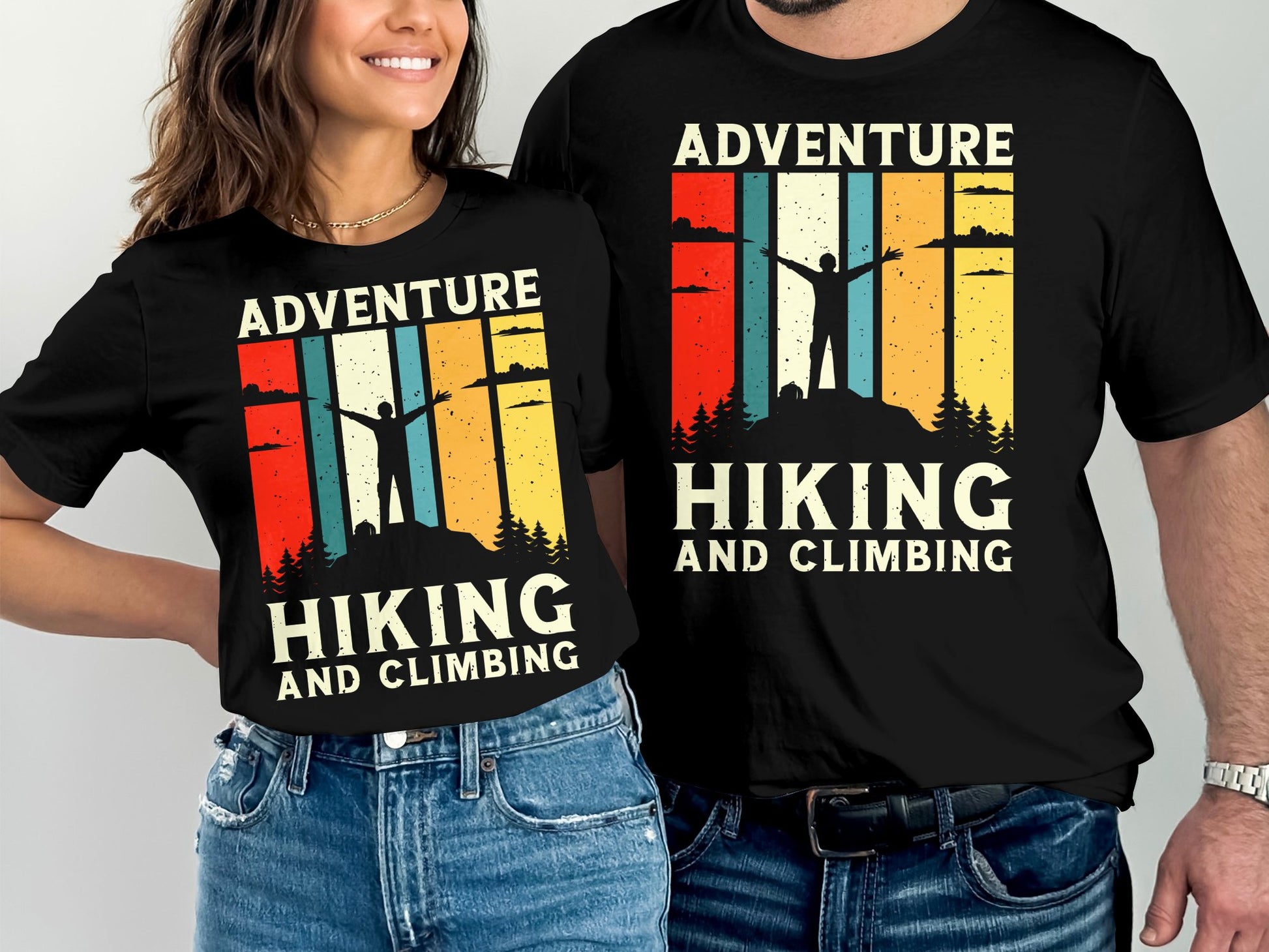 Two people wear matching black t-shirts with a vintage-style mountain adventure graphic.