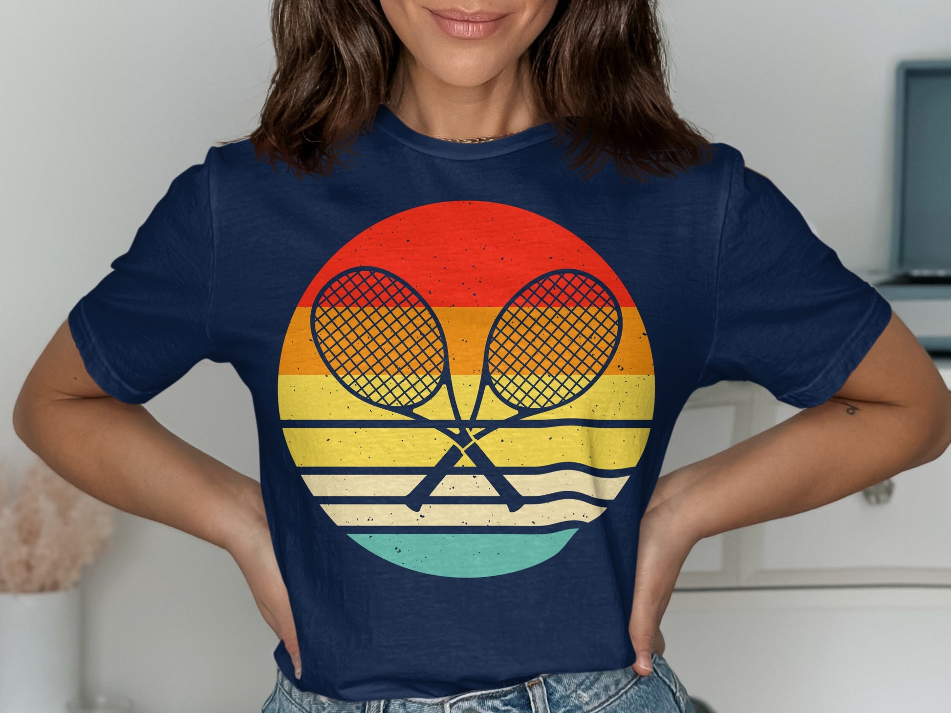Navy t-shirt with crossed tennis rackets inside a retro sunset circle.
