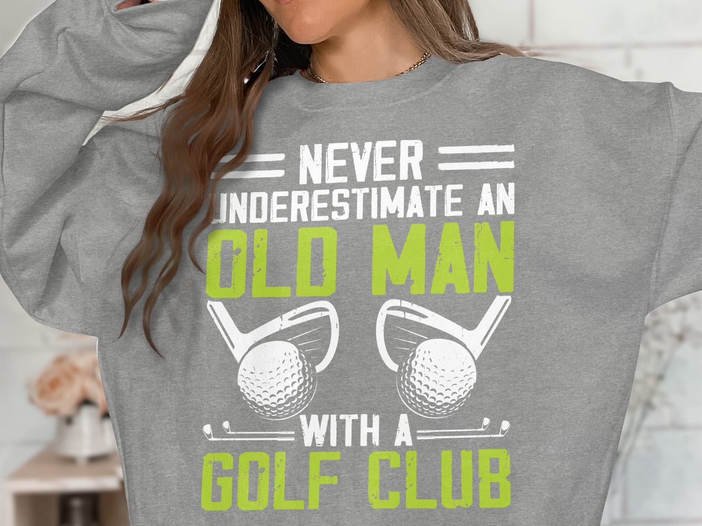 Gray sweatshirt with "Never Underestimate An Old Man With A Golf Club" text, golf clubs, and balls.