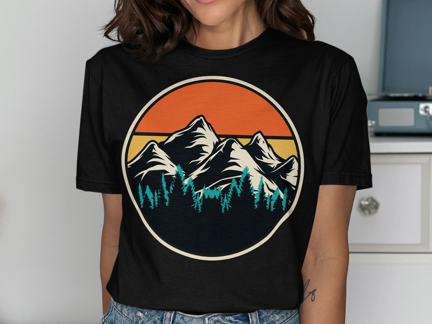 Circular design of mountains and pine trees with sunset gradient.