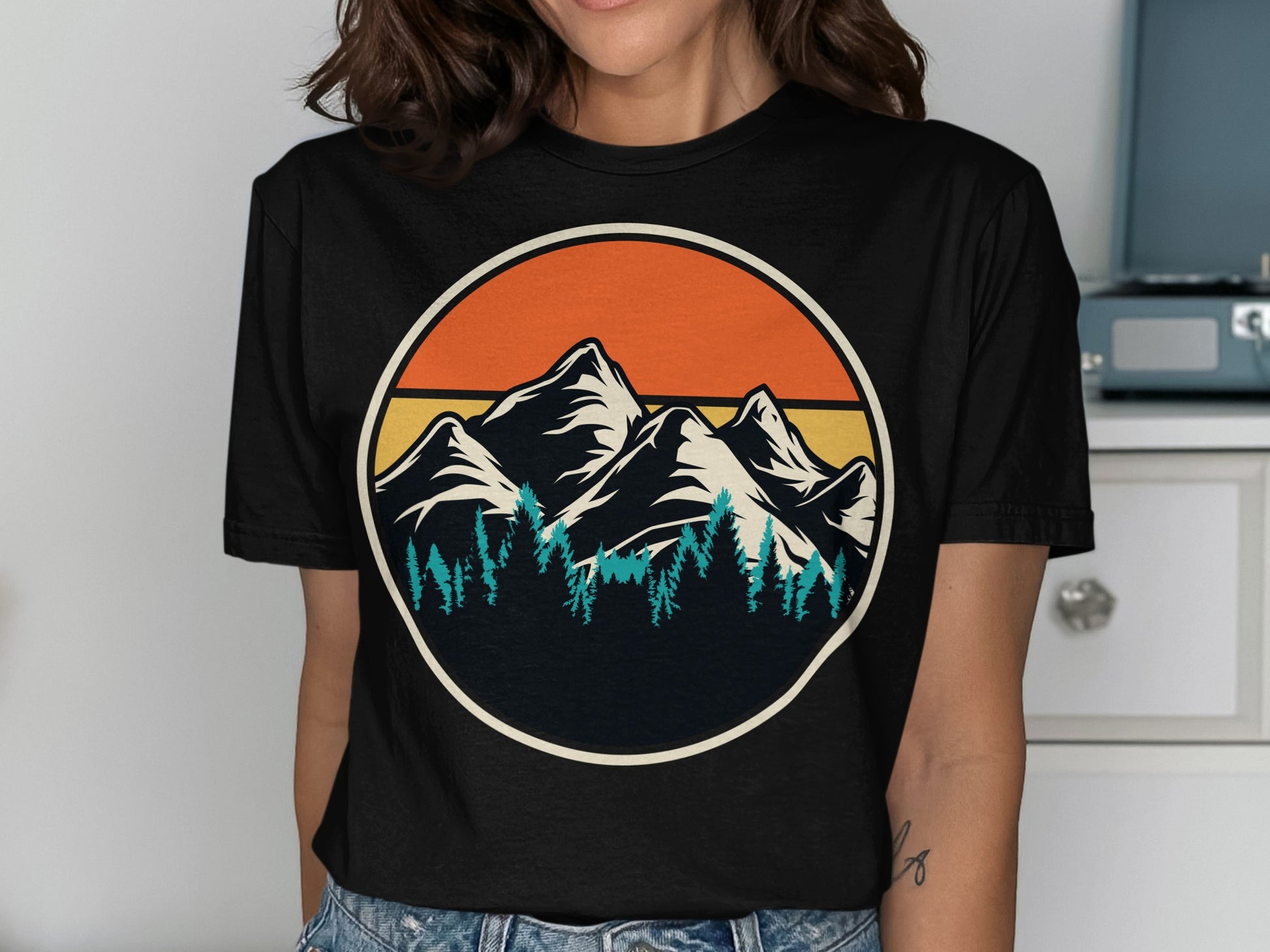 Circular design of mountains and pine trees with sunset gradient.