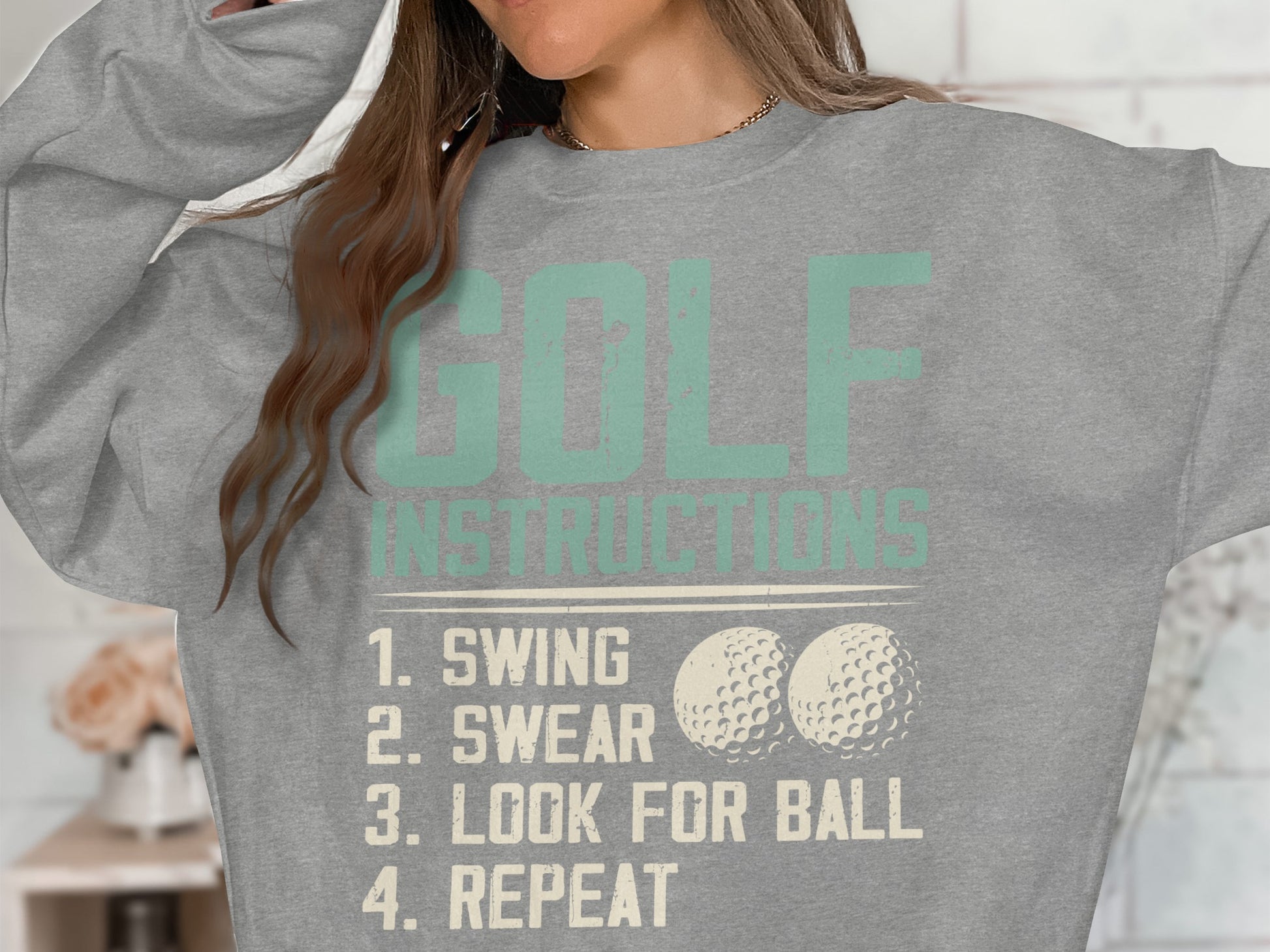 Light grey sweatshirt with "GOLF INSTRUCTIONS" and "SWING, LOOK FOR BALL, REPEAT" text.