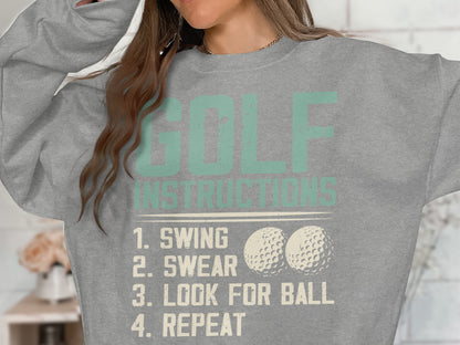 Light grey sweatshirt with "GOLF INSTRUCTIONS" and "SWING, LOOK FOR BALL, REPEAT" text.