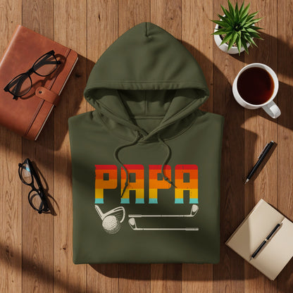 Green hoodie with "PAPA" text, golf clubs, and coffee on wooden table.