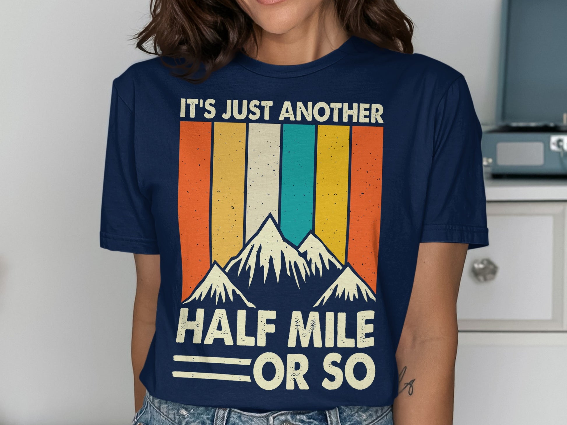Navy t-shirt with mountains and "IT'S JUST ANOTHER HALF MILE OR SO" text.