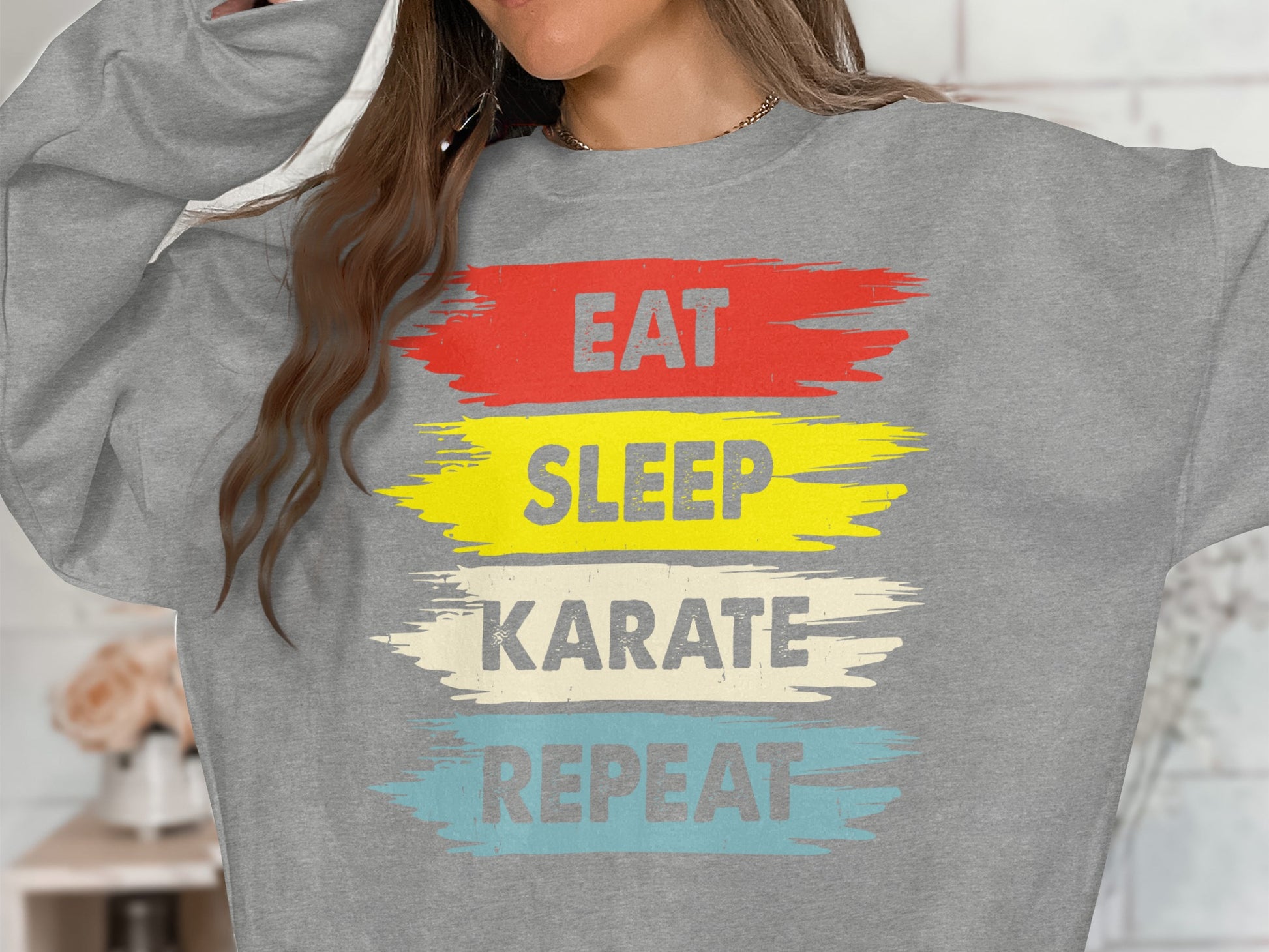 Grey sweatshirt with "Eat Sleep Karate Repeat" text in colorful brush strokes.