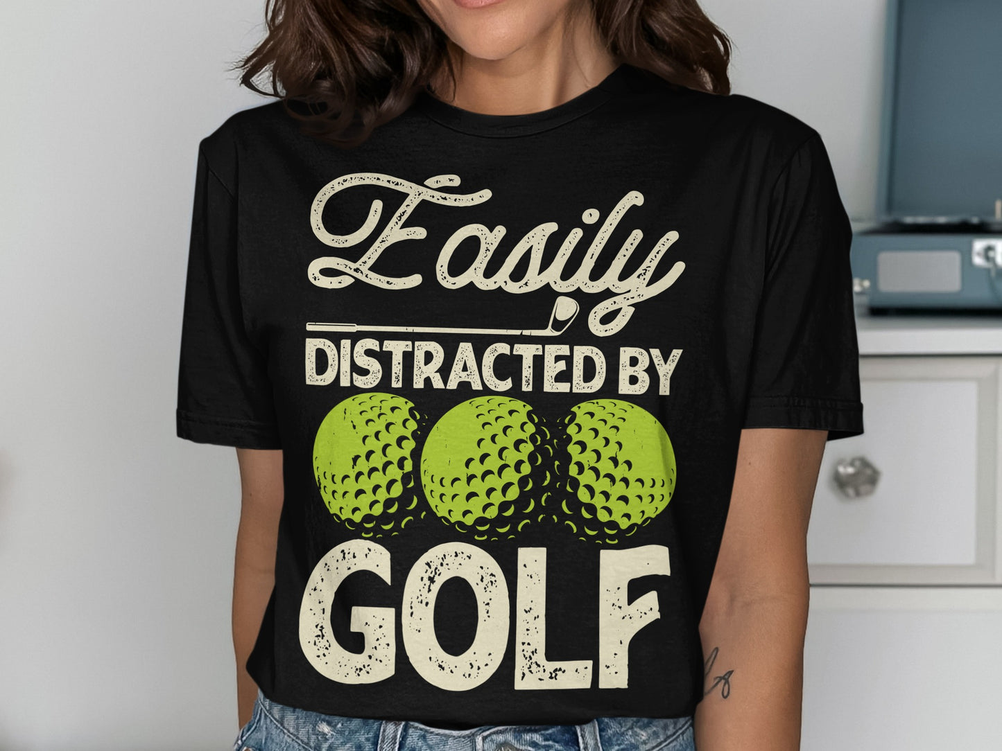 Black t-shirt with "Easily Distracted By Golf" and three golf balls.
