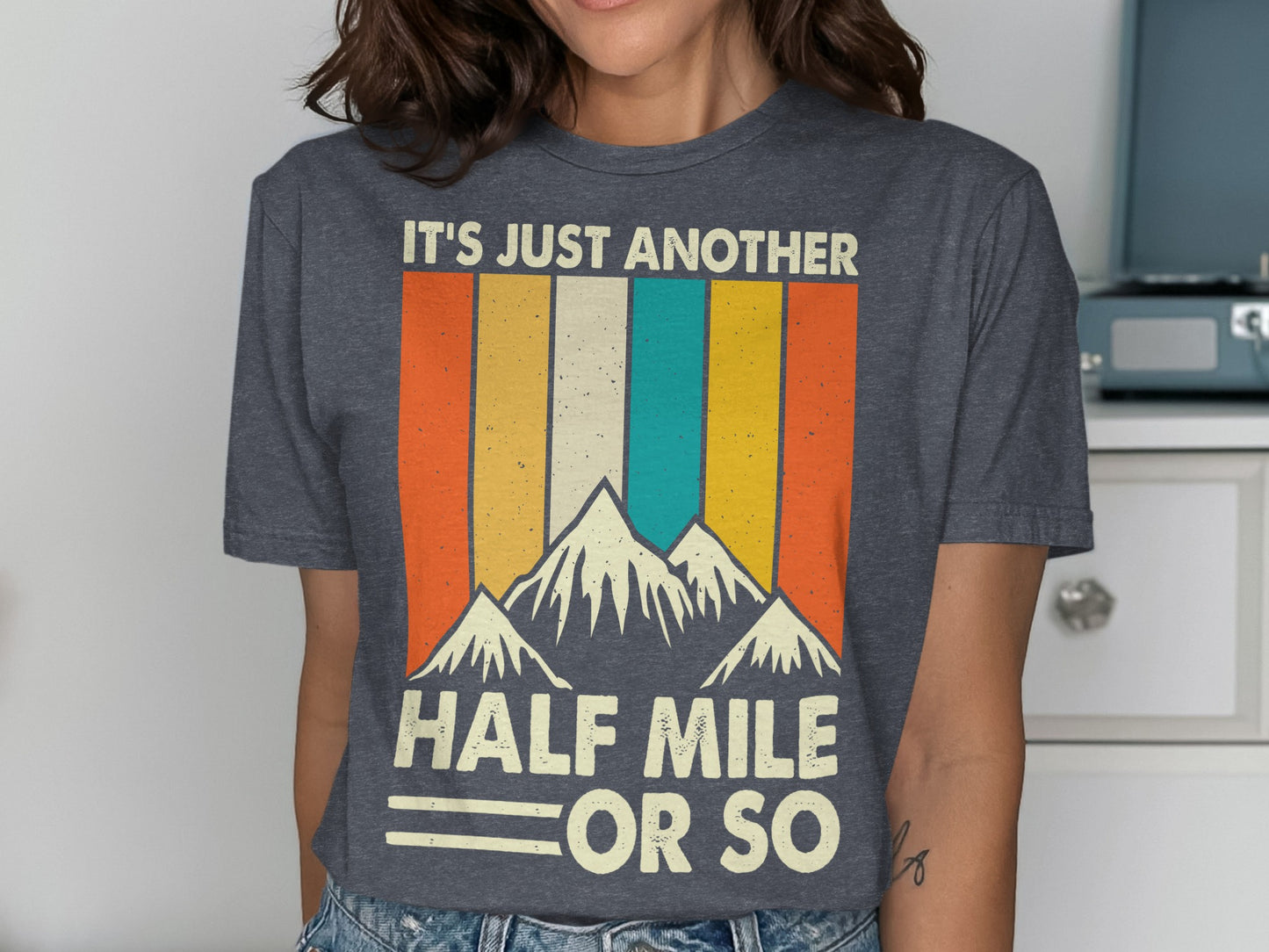Dark gray t-shirt with mountains and "IT'S JUST ANOTHER HALF MILE OR SO" text.
