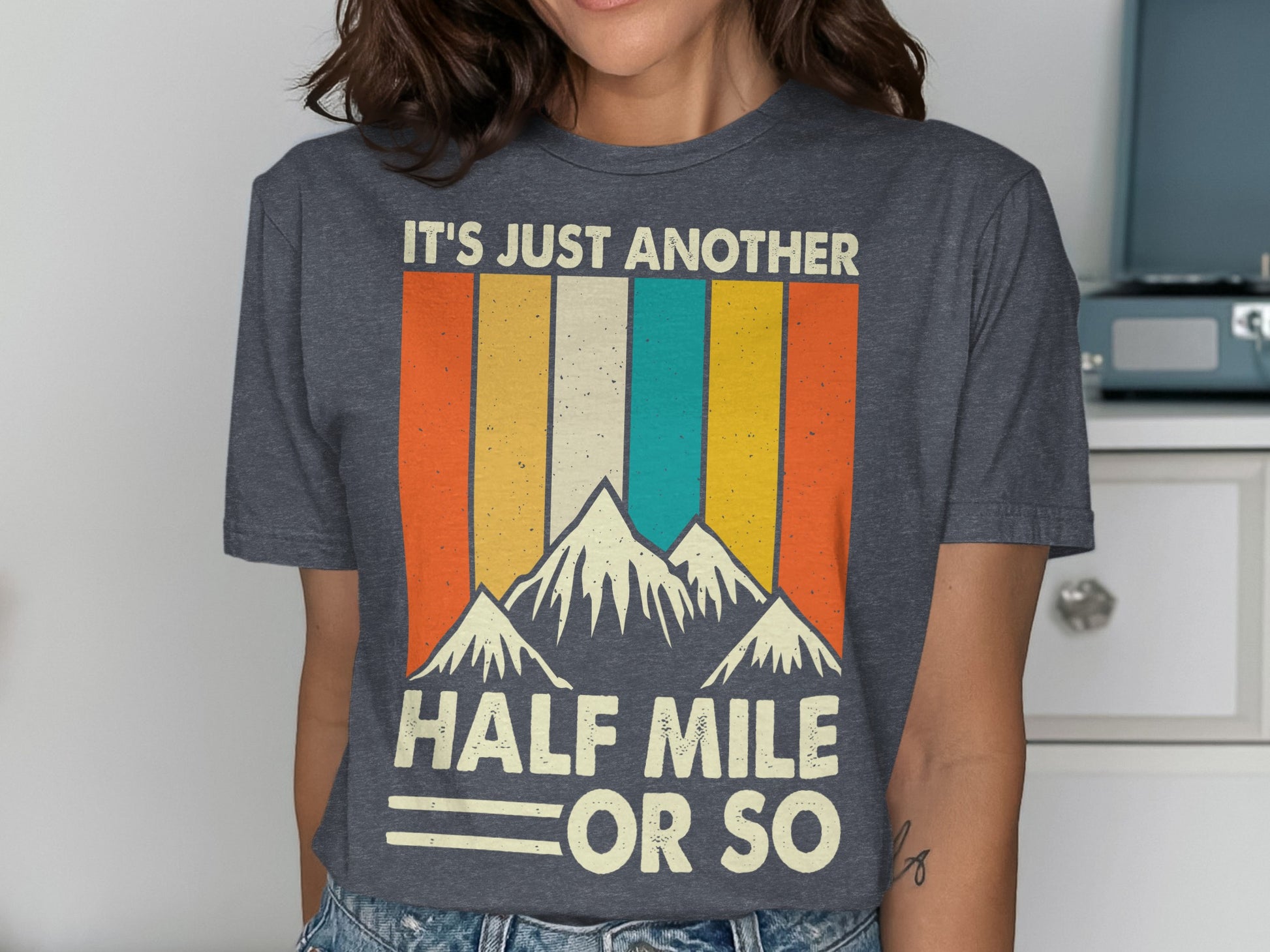 Dark gray t-shirt with mountains and "IT'S JUST ANOTHER HALF MILE OR SO" text.