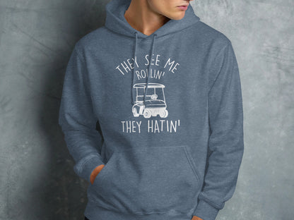 Blue hooded sweatshirt with "They see me rollin' they hatin'" text and golf cart graphic.