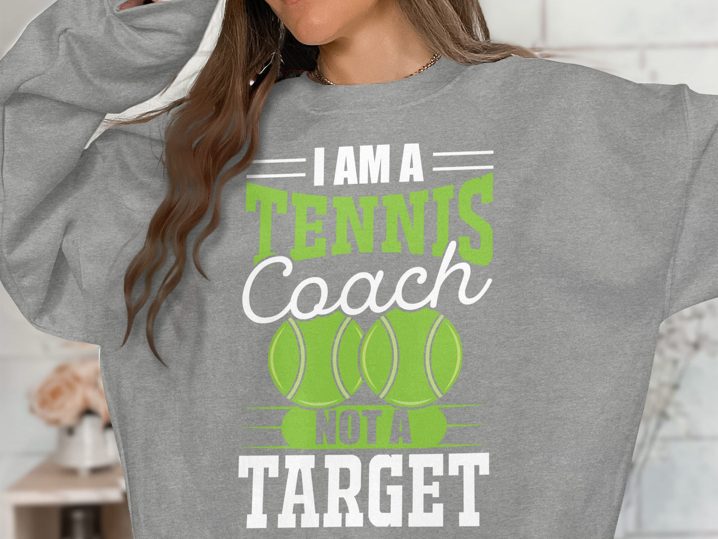 Gray sweatshirt with "I Am A Tennis Coach Not A Target" and tennis balls.