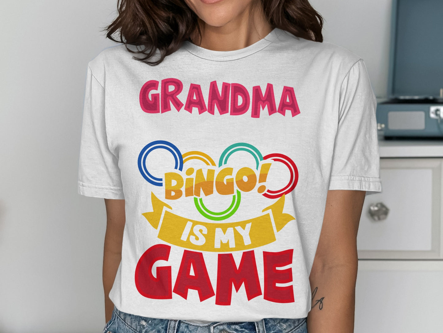 Grandma Bingo is my game text with colorful rings and ribbon graphic on a white t-shirt.