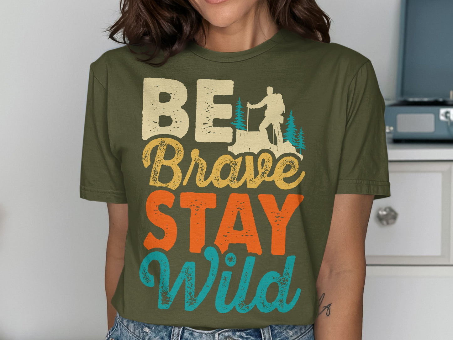 T-shirt with "BE Brave STAY Wild" text and hiker silhouette graphic.