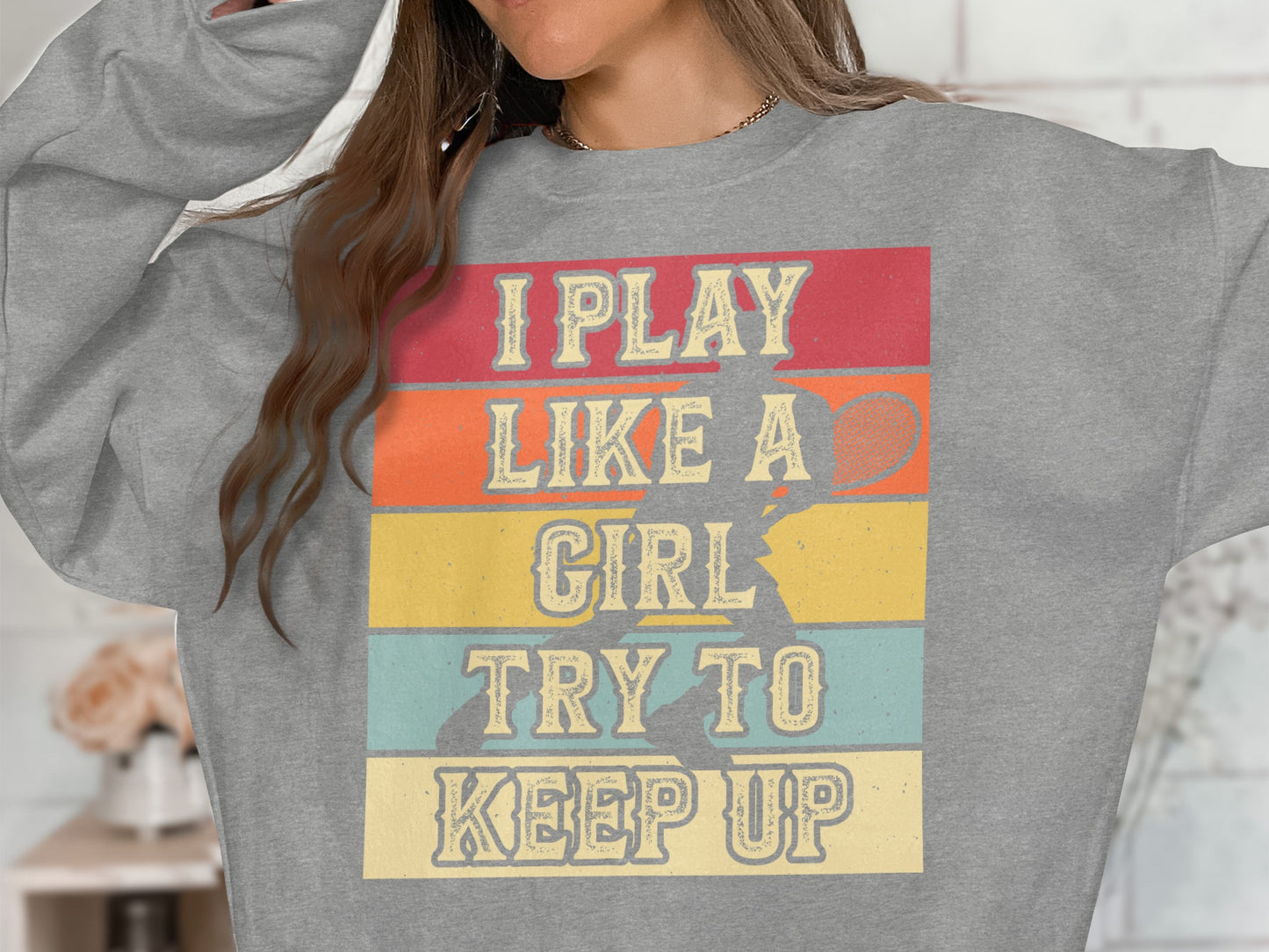 Gray sweatshirt with text "I play like a girl try to keep up" and tennis graphic.