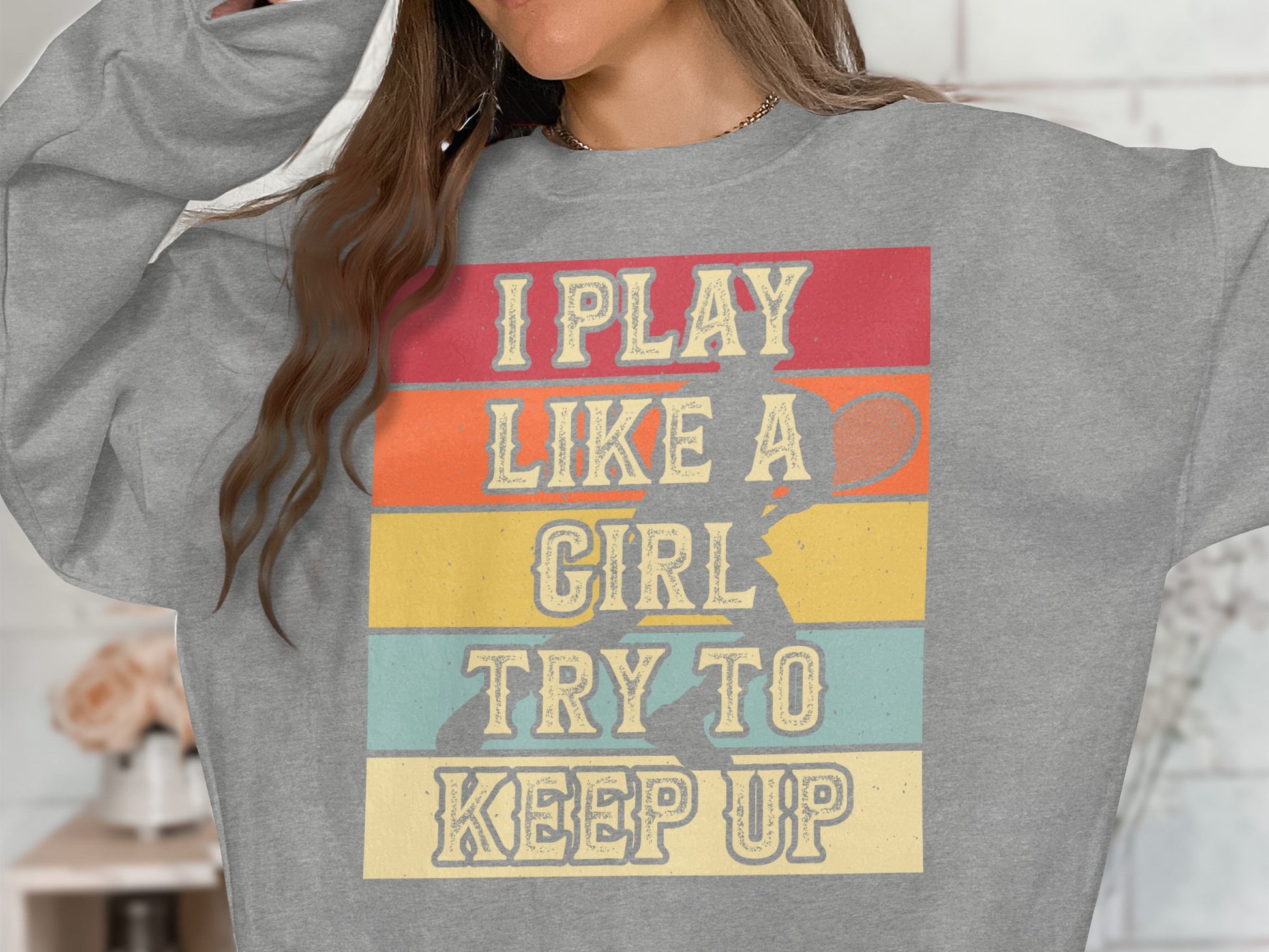 Gray sweatshirt with text "I play like a girl try to keep up" and tennis graphic.